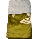 A folded throw blanket with a textured light gray minky fabric on one side and an olive green velvet side with a cream plumeria pattern, displayed on a white marble surface.